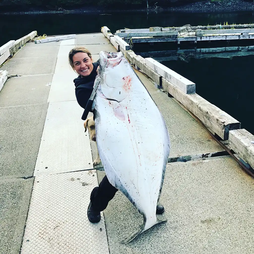 Jamie Davis, general manager of Homer Halibut Hunters is holding up a barn-door sized halibut